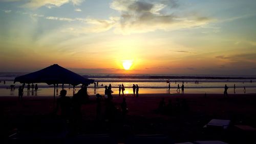 Silhouette people on beach against sky during sunset