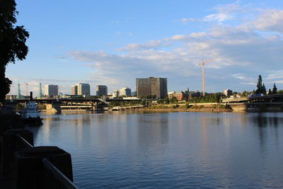 River by buildings in city against sky