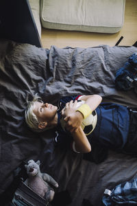 Directly above shot of boy contemplating while lying down in bedroom