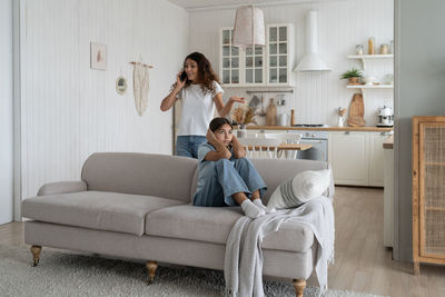 Young woman using mobile phone while lying on sofa at home