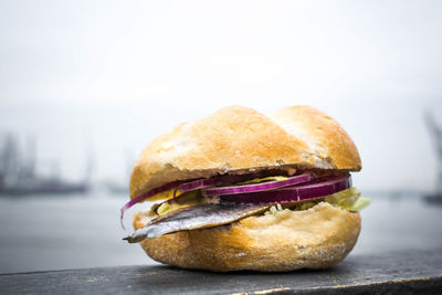 Close-up of burger on railing at harbor against sky