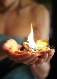 Close-up of woman holding burning candle