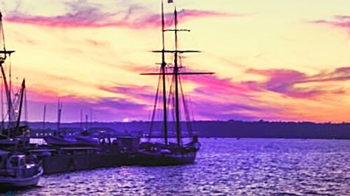 Sailboats in sea at sunset