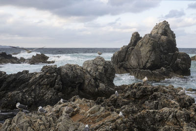 Rock formation by sea against sky