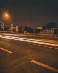 Light trails on road against sky at night