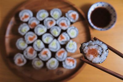 Directly above shot of chopsticks with sushi over plate on table