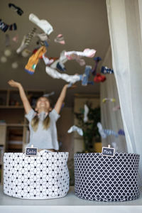 Girl throwing clothes mid air at home