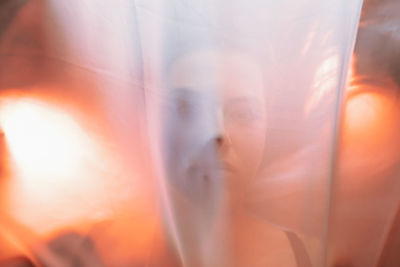 Close-up of woman standing behind orange cloth