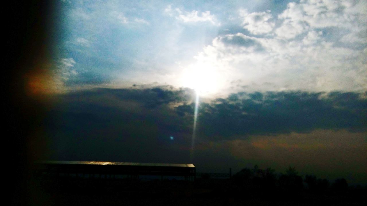 sky, cloud - sky, sunset, silhouette, sun, window, sunbeam, cloudy, weather, sunlight, cloud, low angle view, dark, nature, transportation, no people, lens flare, outdoors, scenics, glass - material