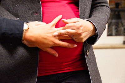 Midsection of pregnant woman with friend hand showing obscene gesture