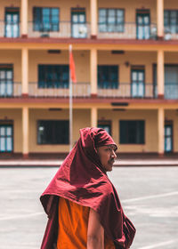 Portrait of woman with red umbrella against building in city