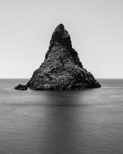 Rock formation in sea against sky