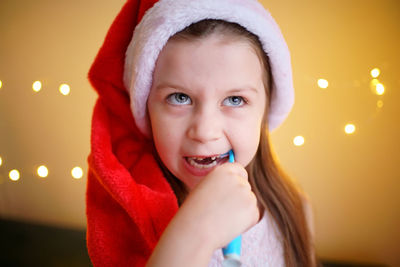 Little girl brushing her teeth in santa hat