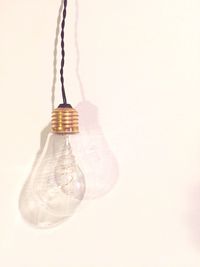 Close-up of light bulb hanging over white background