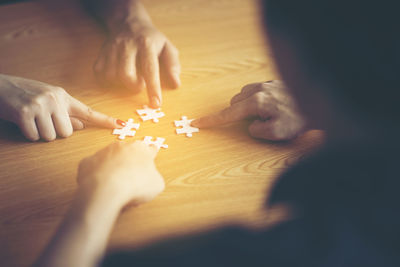 Midsection of people playing with jigsaw puzzle on table