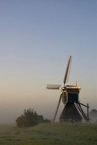 Traditional windmill on landscape against clear sky