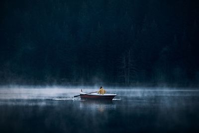 Man sailing in boat at lake at forest