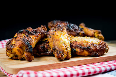 Roasted chicken wings on cutting board against black background