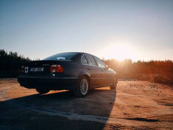 Car on landscape against clear sky during sunset