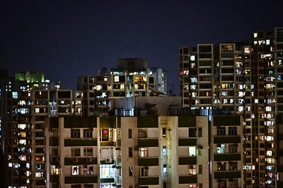 Illuminated buildings against clear sky at night