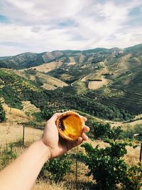 Midsection of person holding ice cream against mountains