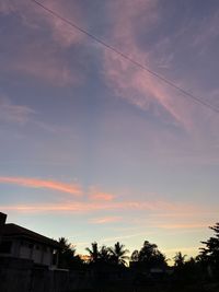 Low angle view of silhouette trees and buildings against sky