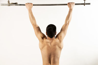 Rear view of shirtless man standing against white background