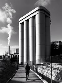 Rear view of woman walking against factory