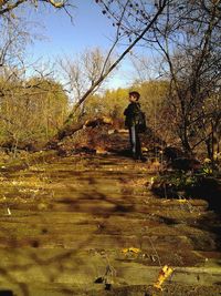 Rear view of man standing by tree against sky