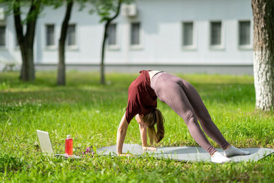 Rear view of senior woman using phone while standing on field