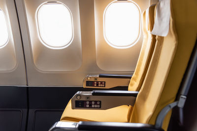Empty yellow color airplane seat with airplane window.