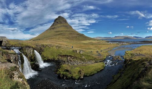 Scenic view of waterfall and iconic mountain against sky