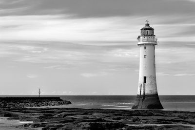 Lighthouse by sea against sky