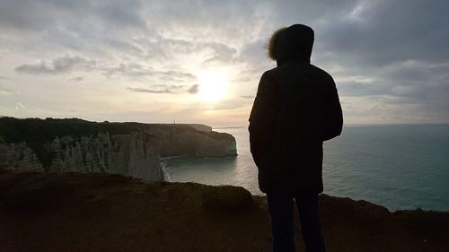 Rear view of silhouette man looking at sea against sky