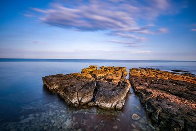 Rock formations on sea shore against sky