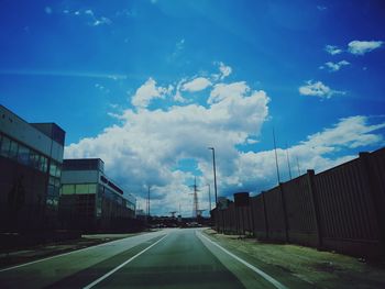 Road amidst buildings in city against sky