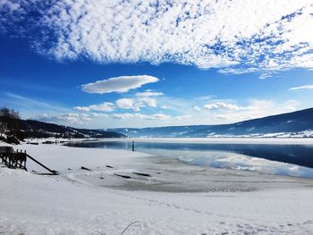 Scenic view of sea and snowcapped mountains against sky