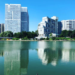 Lake and modern buildings against clear sky