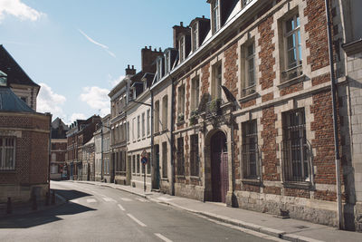 Empty road amidst buildings against sky