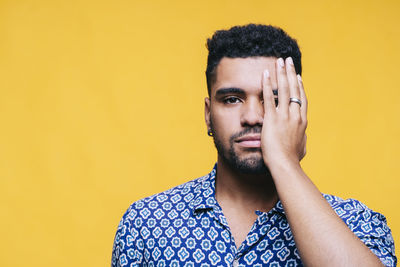 Portrait of young man looking away against yellow background