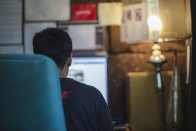 Rear view of man sitting at home