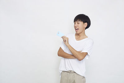 Smiling young woman standing against white background