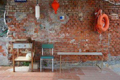 Empty chair and tables against brick wall