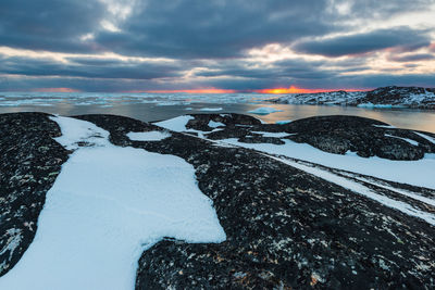 Sunset at coastal landscape with icebergs in fjord