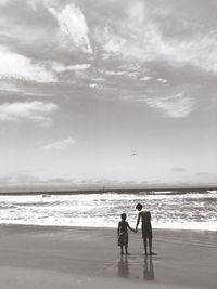 Men standing on beach against sky