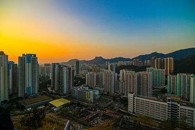 Modern buildings in city against sky during sunset