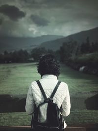 Rear view of woman standing by railing against landscape