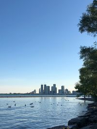 Buildings by sea against clear blue sky