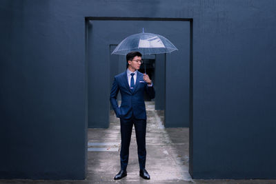 Full length portrait of young man standing against wall