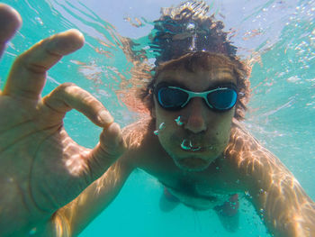 Portrait of man gesturing ok sign while swimming in sea